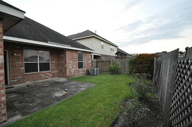a view of a yard in front of a house with large windows