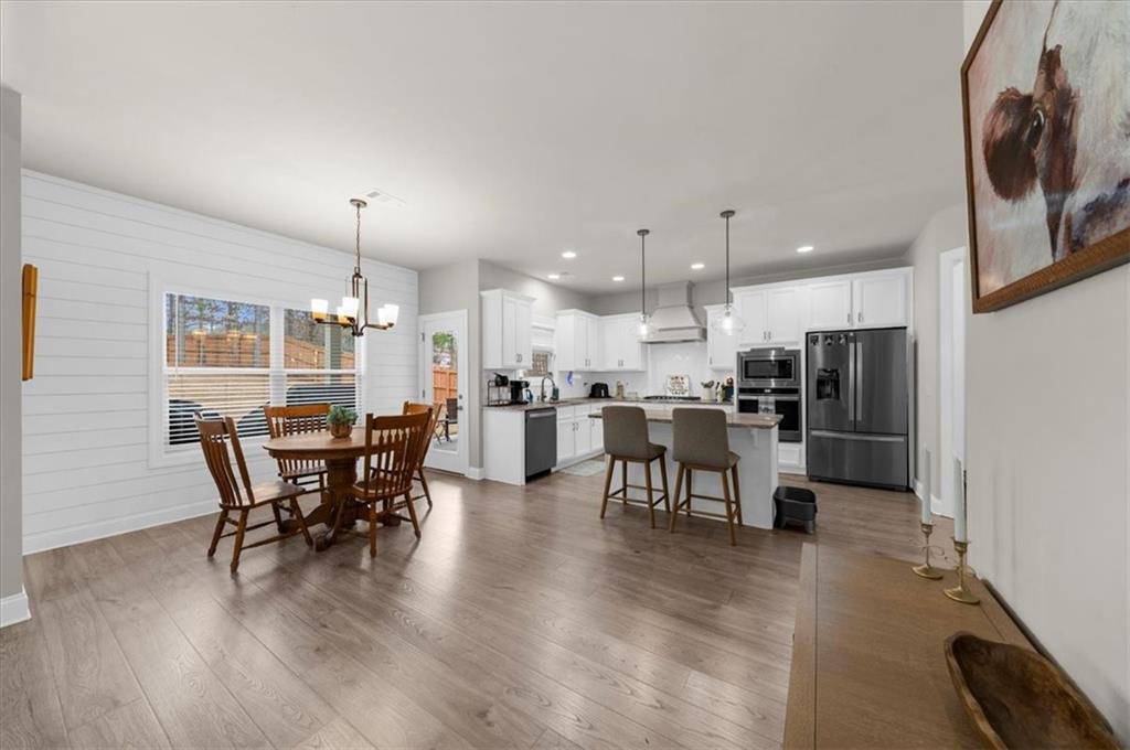 182 Bella Drive Monroe, GA 30655 - Photo 20 of 63 a view of a dining room and livingroom with furniture wooden floor a rug a fireplace and a painting