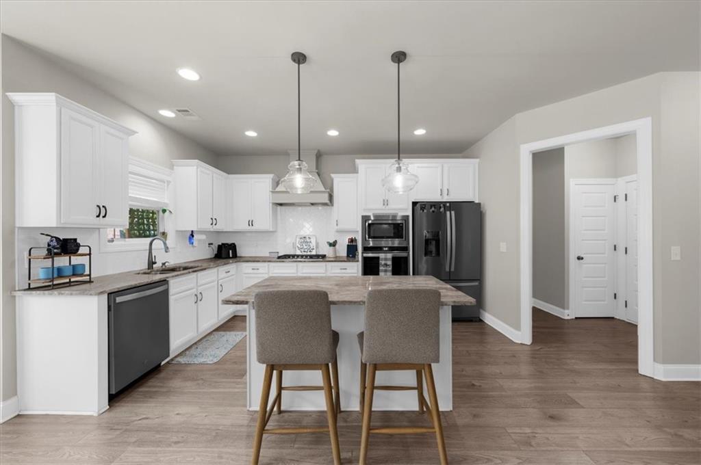 182 Bella Drive Monroe, GA 30655 - Photo 23 of 63 a kitchen with stainless steel appliances granite countertop a refrigerator a stove a sink dishwasher a dining table and chairs with wooden floor