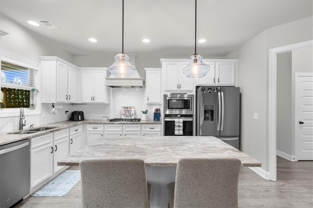 182 Bella Drive Monroe, GA 30655 - Photo 24 of 63 a kitchen with stainless steel appliances kitchen island granite countertop a sink a stove a refrigerator and cabinets