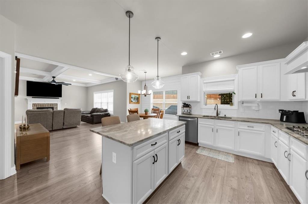182 Bella Drive Monroe, GA 30655 - Photo 27 of 63 a open kitchen with stainless steel appliances granite countertop a stove top oven a sink dishwasher a dining table and chairs with wooden floor