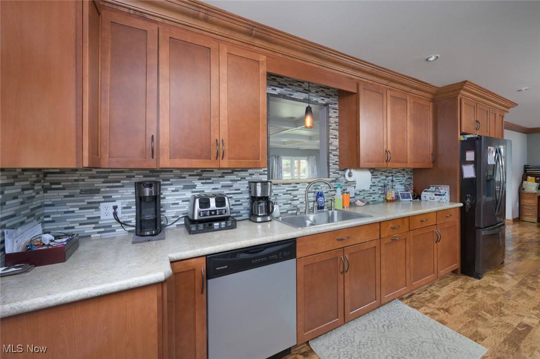 3234 Bell Wick Road Hubbard, OH 44425 - Photo 19 of 27 Kitchen featuring brown cabinets, tasteful backsplash, appliances with stainless steel finishes, light countertops, and ornamental molding