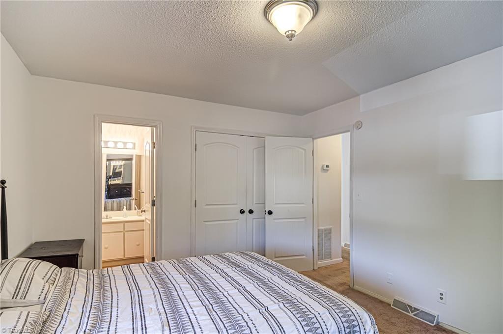 2215 Shadow Valley Road, Unit B High Point, NC 27265 - Photo 21 of 33 Alternate view of primary bedroom showing en suite bathroom, double door closet, and hallway that opens to second and third bedroom.