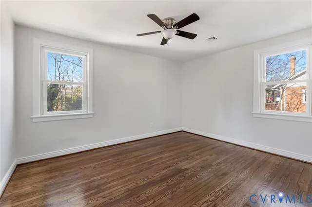 a view of empty room with wooden floor and window