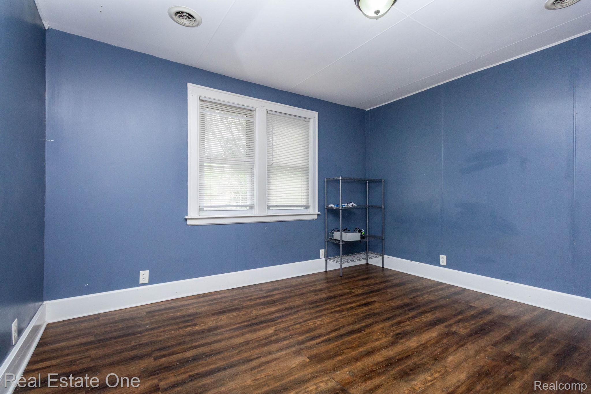 5485 Springwells Street Detroit, MI 48210 - Photo 28 of 47 Room featuring wood-finish flooring, white baseboards, and blue walls