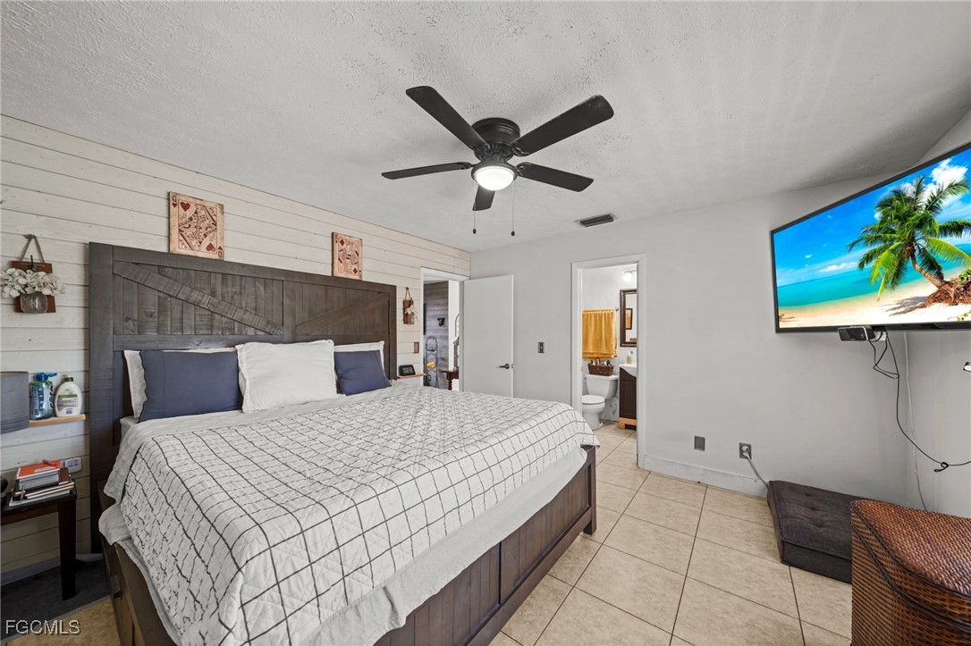 4121 16th Avenue Northeast Naples, FL 34120 - Photo 18 of 35 a bedroom with a bed a dresser and a chandelier