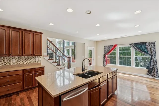 a kitchen that has a sink and a stove with wooden floor