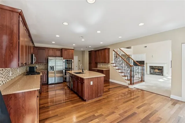 a living room with stainless steel appliances kitchen island granite countertop a large kitchen island a stove a refrigerator a sink and a cabinets with wooden floor