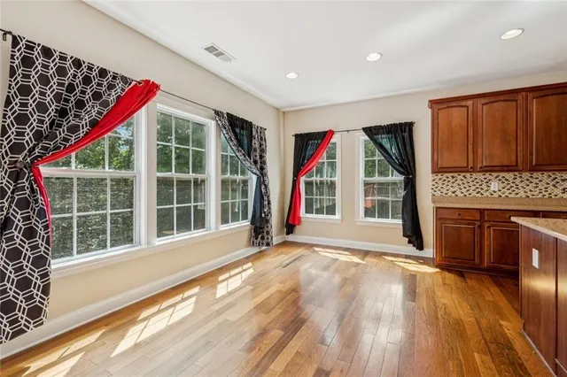 a view of an empty room with wooden floor and windows
