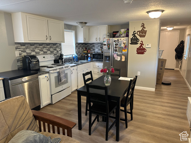 1375 West 500th North, Unit 95 Provo, UT 84601 - Photo 4 of 19 Kitchen featuring stainless steel appliances, dark countertops, white cabinetry, wood finished floors, and a textured ceiling