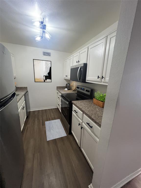 4639 Williams Road, Unit 209 Benbrook, TX 76116 - Photo 4 of 11 Kitchen with appliances with stainless steel finishes, dark wood-style floors, white cabinetry, a textured ceiling, and dark countertops