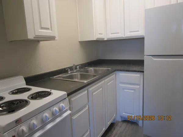 a kitchen with granite countertop a sink stove and cabinets