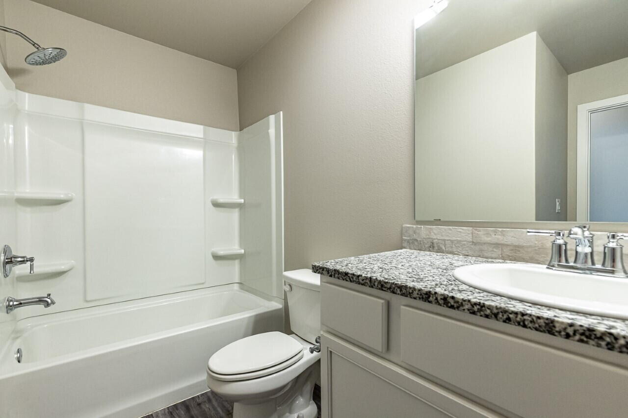 1901 Langford Avenue, Unit B Lubbock, TX 79407 - Photo 7 of 11 a bathroom with a granite countertop sink toilet and shower