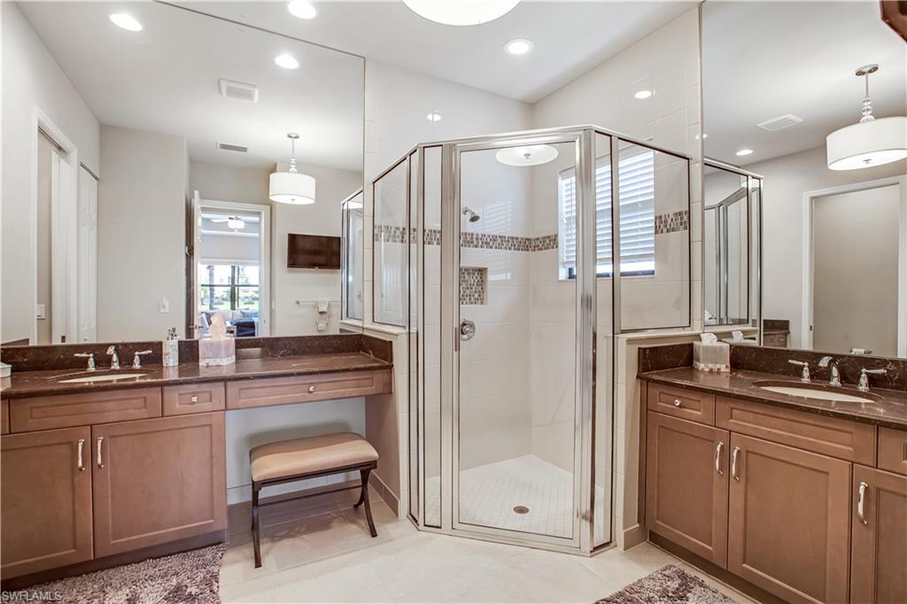 4310 Aurora Street Naples, FL 34119 - Photo 8 of 17 a bathroom with a double vanity sink a mirror a bathtub and shower
