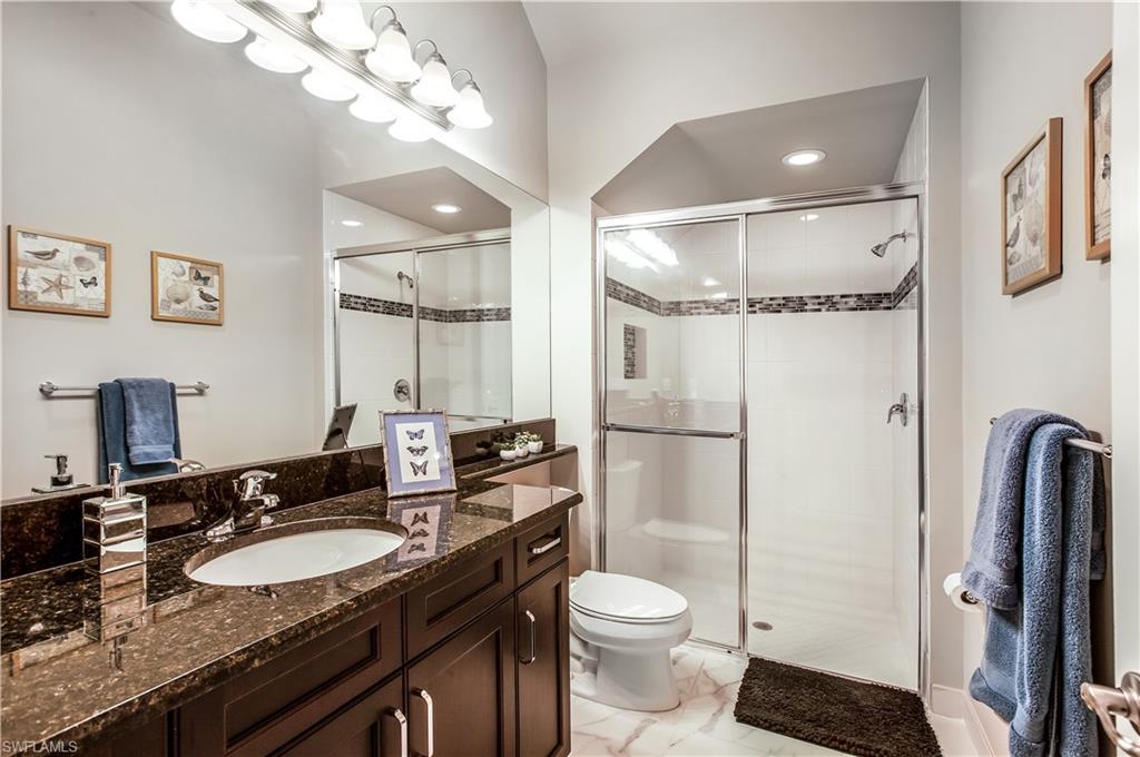 4310 Aurora Street Naples, FL 34119 - Photo 9 of 17 a bathroom with a granite countertop sink a toilet a mirror and shower
