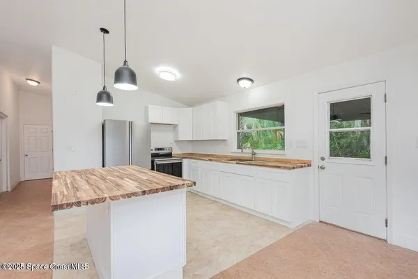 a kitchen with kitchen island a counter top space appliances and a chandelier