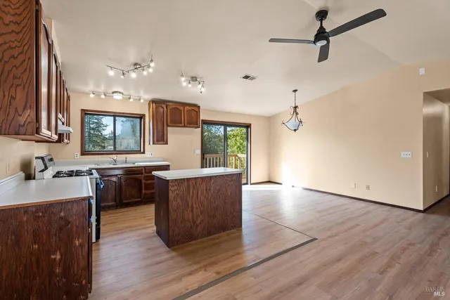 a kitchen with granite countertop a stove a sink a refrigerator and wooden floor