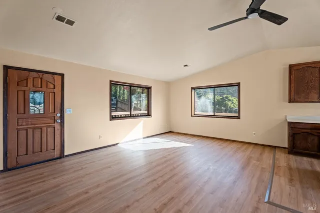 a view of an empty room with a window and wooden floor