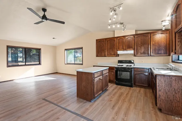a kitchen with granite countertop a stove top oven a sink dishwasher and a oven with wooden floor