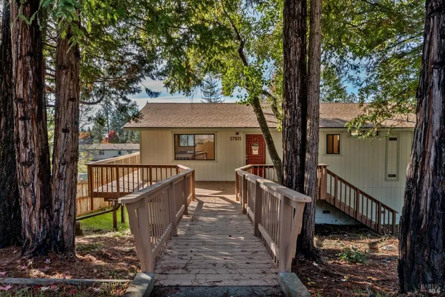 a view of a house with large trees and a deck
