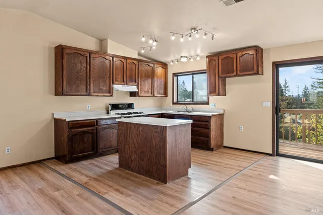 a kitchen with stainless steel appliances granite countertop a stove a sink dishwasher and a refrigerator with wooden floor