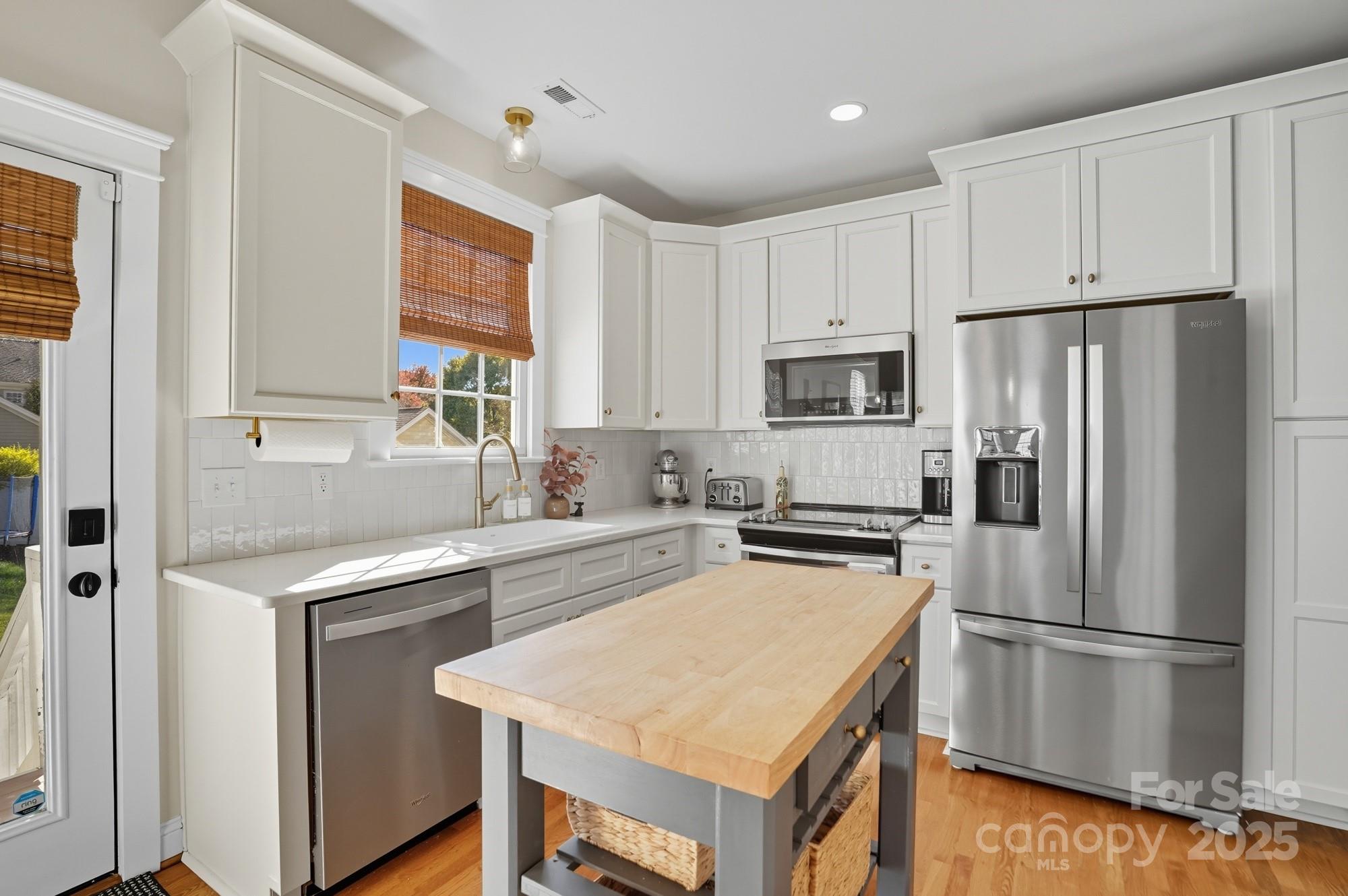 911 Cara Court Fort Mill, SC 29708 - Photo 17 of 48 a kitchen with a refrigerator a stove a sink and white cabinets with wooden floor