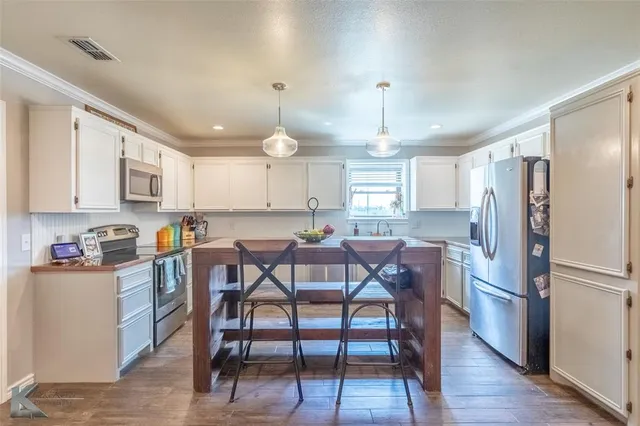a kitchen with stainless steel appliances a dining table chairs refrigerator and sink