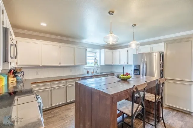 a kitchen with stainless steel appliances a sink a stove a table and chairs