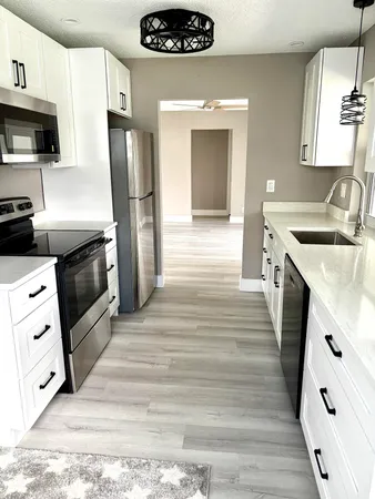 a kitchen with stainless steel appliances white cabinets a stove top oven a sink and dishwasher