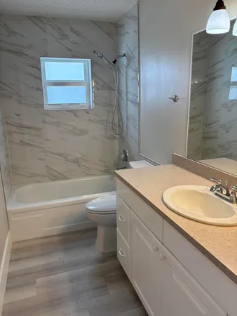 a bathroom with a granite countertop bathtub sink vanity mirror and toilet