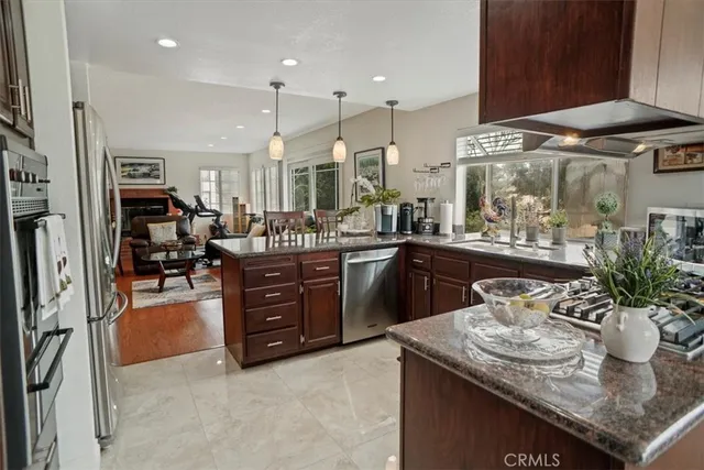 a kitchen with stainless steel appliances granite countertop a sink a stove and a wooden floors