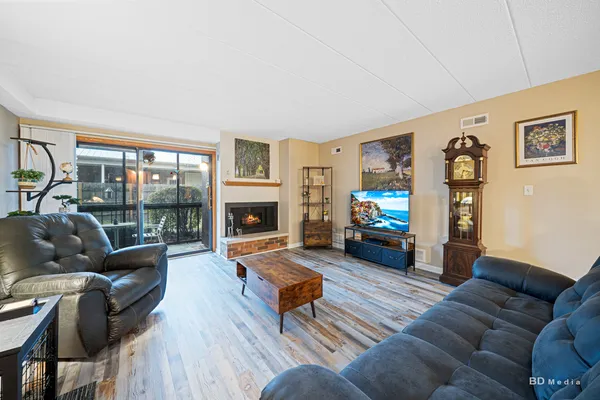 a living room with furniture a fireplace a flat screen tv and a large window