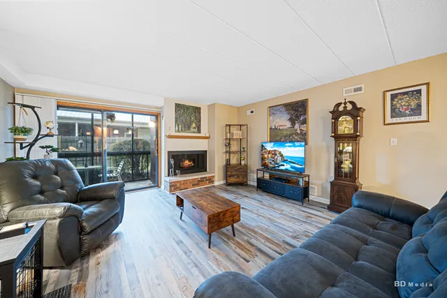 a living room with furniture a fireplace a flat screen tv and a large window