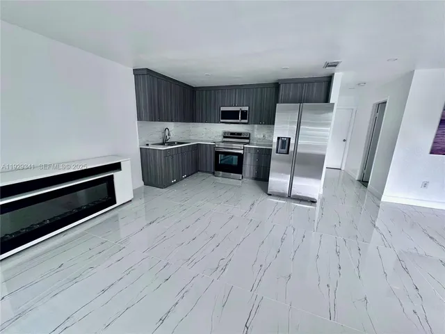 a kitchen with stainless steel appliances a stove a sink and wooden floors