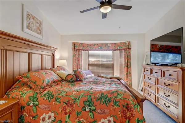 a bedroom with a bed and a flat tv screen on dresser
