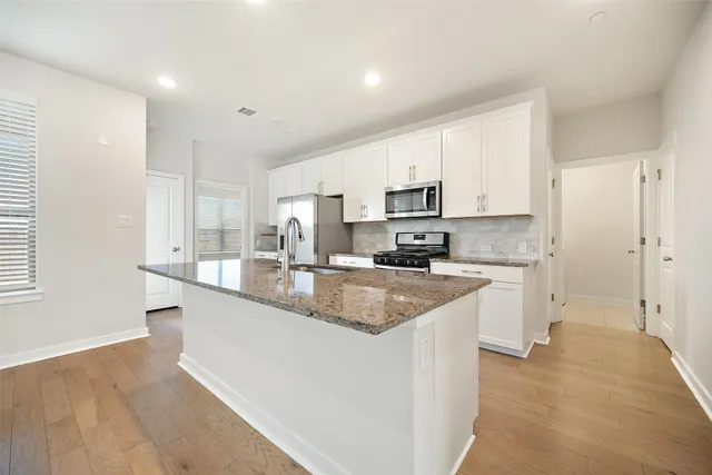 a large kitchen with stainless steel appliances granite countertop a sink a stove a refrigerator a center island and cabinets