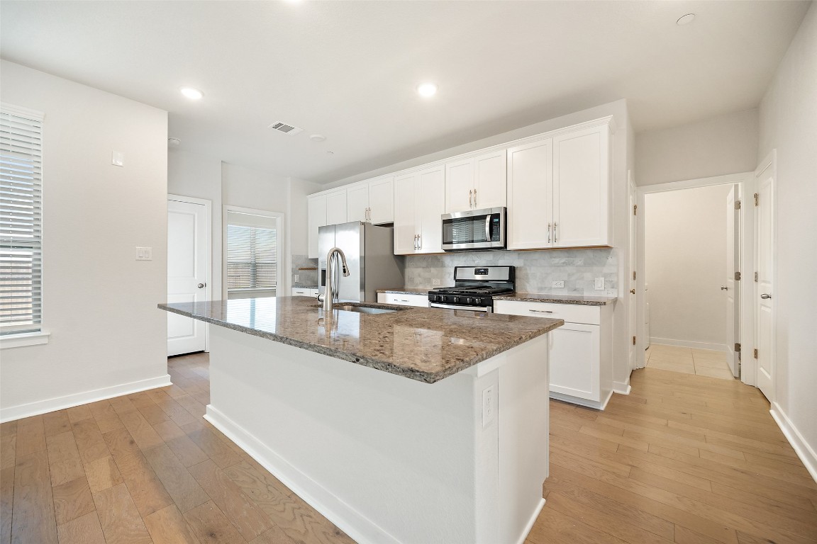 2500 Forest Creek Drive, Unit 603 Round Rock, TX 78665 - Photo 4 of 16 a large kitchen with stainless steel appliances granite countertop a sink a stove a refrigerator a center island and cabinets