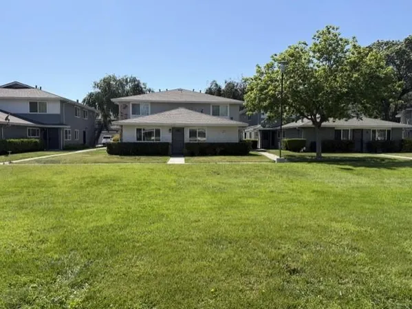 a view of a house with a big yard and large trees