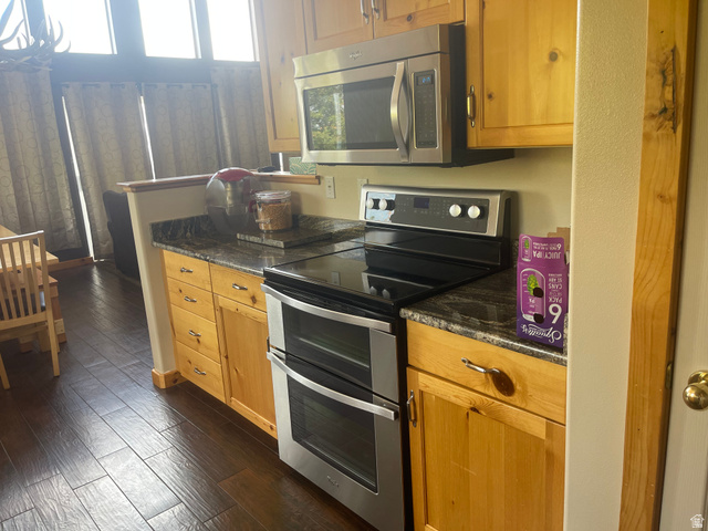 553 Raspberry Patch Road Garden City, UT 84028 - Photo 12 of 21 Kitchen featuring stainless steel appliances, dark wood-style flooring, dark stone countertops, and wood finish cabinets