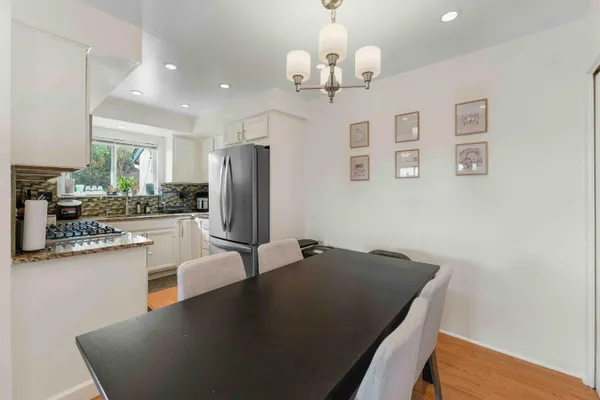 a kitchen with kitchen island stainless steel appliances a refrigerator a stove a sink dishwasher a oven with white cabinets and wooden floor