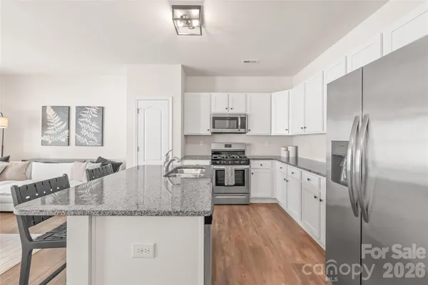 a kitchen with granite countertop a refrigerator a stove a sink a dining table and chairs