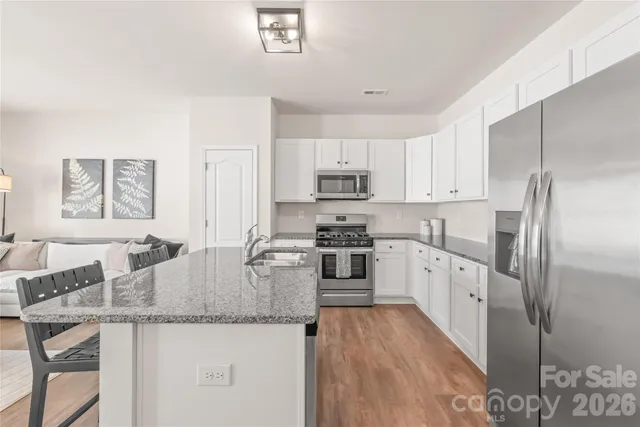 a kitchen with granite countertop a refrigerator a stove a sink a dining table and chairs