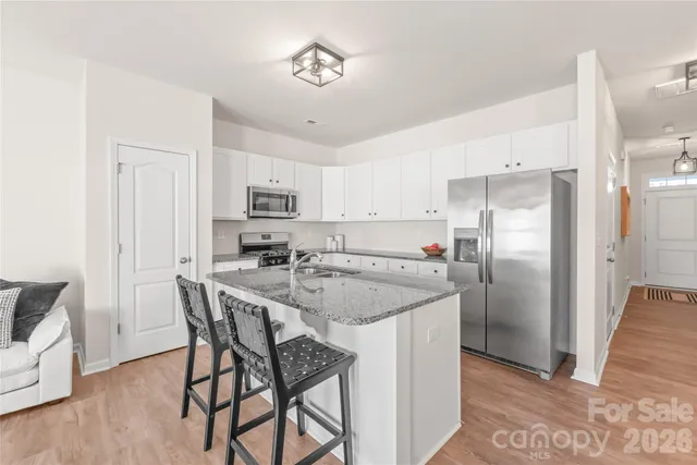 a kitchen with stainless steel appliances granite countertop a refrigerator a stove a sink a dining table and chairs