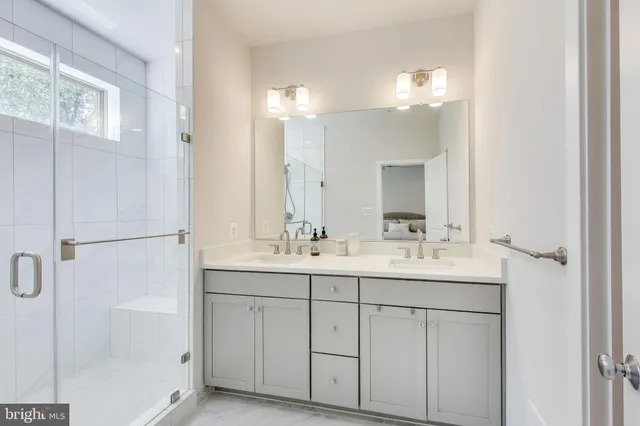 a bathroom with a double vanity sink a mirror and a shower