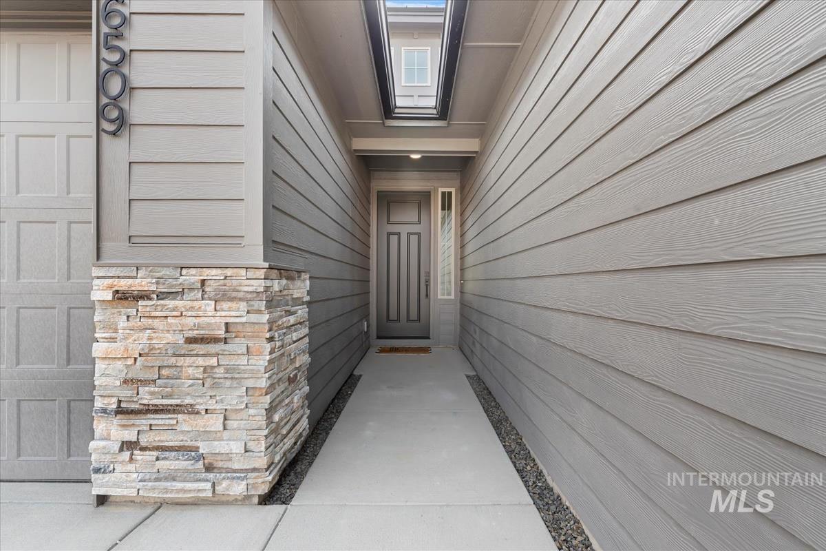 2166 East Rodeo Street Kuna, ID 83634 - Photo 2 of 43 Entryway featuring stacked stone accent, plank siding, and a covered porch
