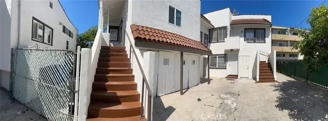 a view of a house with a small yard and potted plants