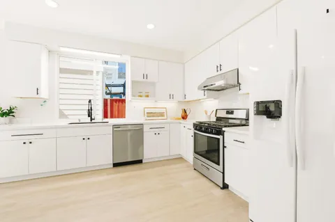 a kitchen with white cabinets stainless steel appliances and sink