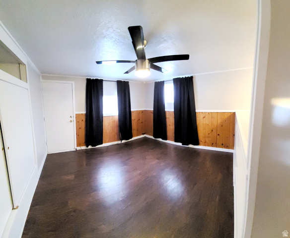 684 East 400 North Logan, UT 84321 - Photo 25 of 27 Spacious room featuring rich wood-finish flooring, half-wall wood paneling, and a contemporary ceiling fan with integrated lighting