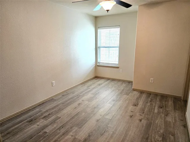 an empty room with wooden floor chandelier fan and windows