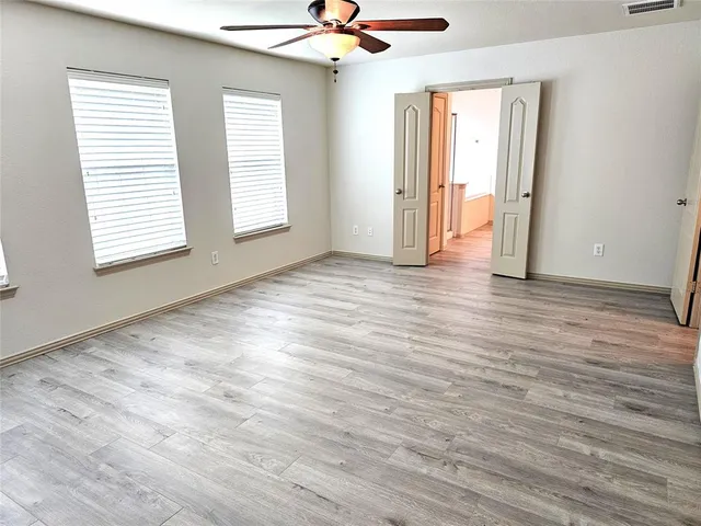 an empty room with wooden floor and windows